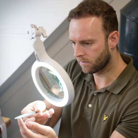 Rick van der Linden prüft ein geschliffenes Instrument unter der Lupe